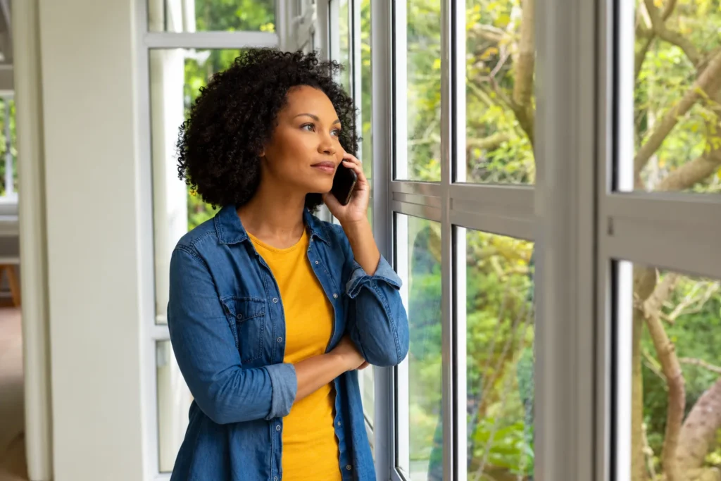 Woman talking on the phone by a window.
