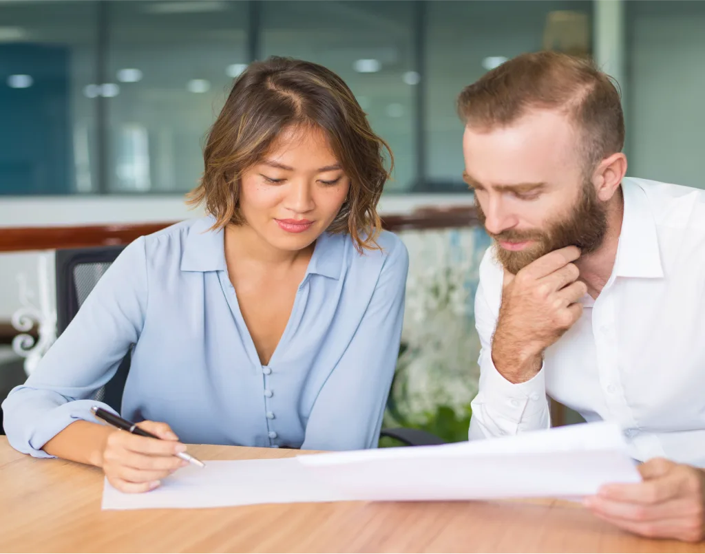 Two people reviewing a printed estimate at a desk.